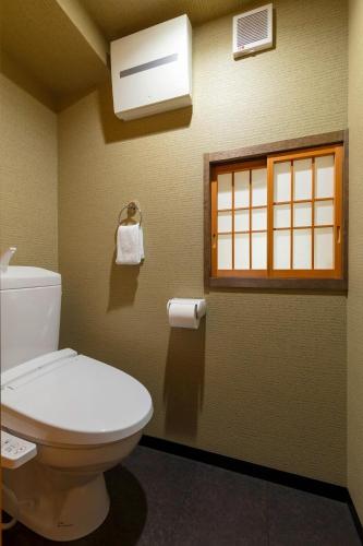 a bathroom with a toilet and a window at Yoshimigura Machiya House in Kyoto