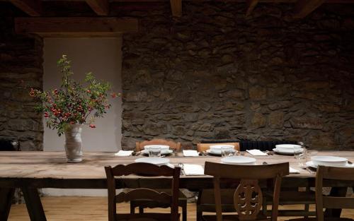 a wooden table with chairs and a vase with flowers at Cal Calsot Casa Rural "Adults Only" in Montellá