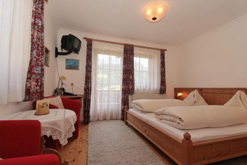a bedroom with two beds and a chair and a window at Pension Gatterer in Maria Luggau