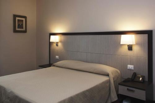 a bedroom with a bed and two lights on the wall at Hotel Alpi Resort in Turin