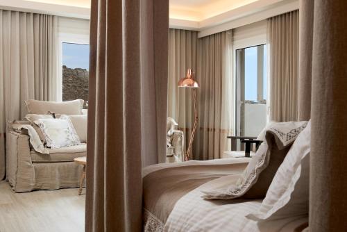 a bedroom with a bed and a chair and a window at Palladium Hotel in Platis Yialos Mykonos
