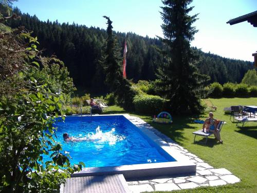ein Schwimmbad in einem Garten mit Menschen darin in der Unterkunft Gästehaus Elisabeth in Radstadt
