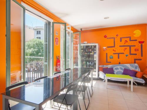 バルセロナにあるノー リミット ホステル グラフィティのガラスのテーブルと椅子が備わるオレンジ色の客室です。
