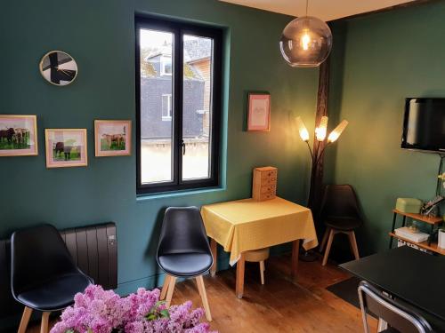 ルーアンにあるAppartement typique Rouen centre tout confortのテーブルと椅子、窓が備わる客室です。