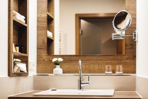 uma casa de banho com um lavatório e um espelho em Hotel Edita em Scheidegg