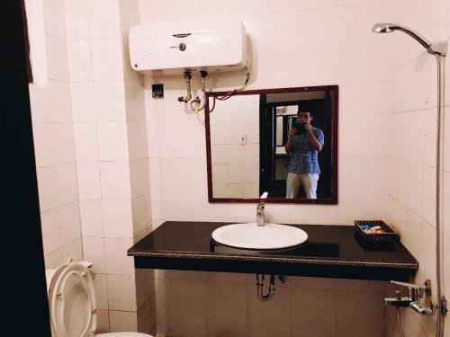 a person taking a picture of a bathroom with a mirror at Khách sạn Hồ Gươm in Sầm Sơn