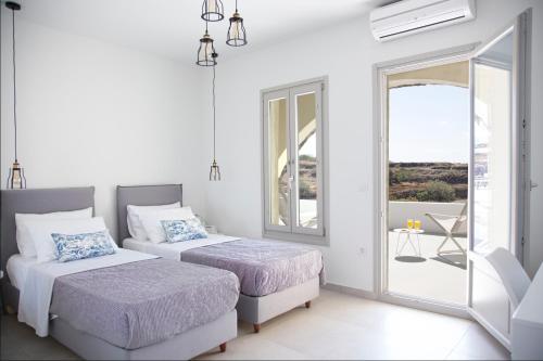 two beds in a white room with a balcony at Aplai Dome in Oia