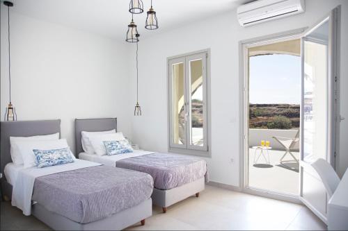 2 bedden in een witte kamer met een balkon bij Aplai Dome in Oia
