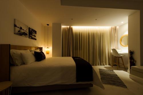 a bedroom with a large white bed and a desk at Alfa Hotel in Parga