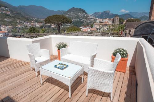 a balcony with white chairs and a table with a view at Mimì B&B in Ravello
