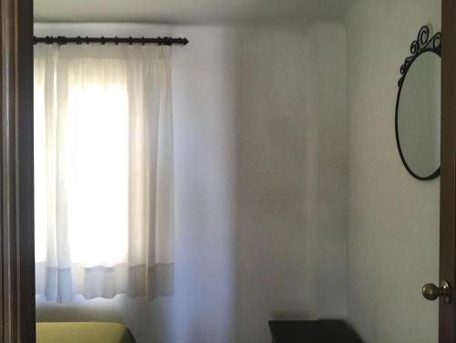 a room with a window with white curtains and a mirror at Hostal Esperanza in Benajarafe