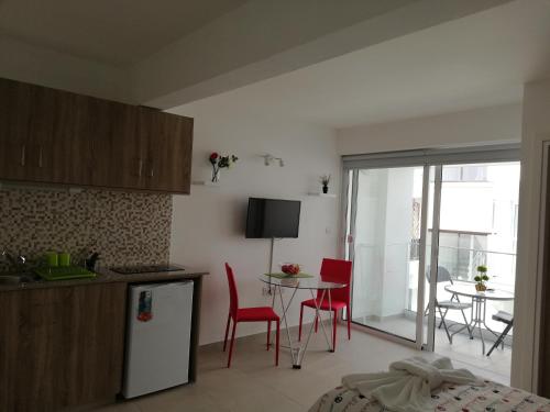 a kitchen with red chairs and a table in a kitchen at Chicos Studios in Ayia Napa