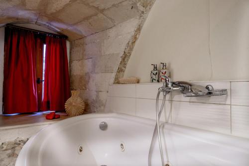 eine Badewanne im Bad mit einem roten Vorhang in der Unterkunft Leo Hotel in Rethymno