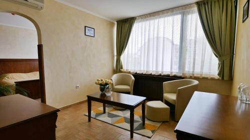 a living room with a table and chairs in a room at Central West Hotel in Sofia