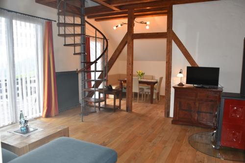 a living room with a spiral staircase and a television at Hotel & Chalets Herrihof in Todtnauberg