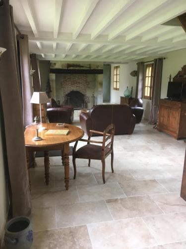 a living room with a table and chairs and a fireplace at L'auberge du Mont in Le Breuil-en-Auge