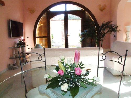 a glass table with a bouquet of flowers on it at Keira B&B in Quartucciu