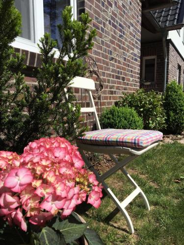 a chair sitting in the yard next to pink flowers at Lesny Apartament in Ostrzyce