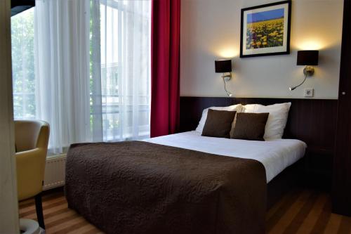 1 dormitorio con 1 cama grande y cortinas rojas en Prinsengracht Hotel en Ámsterdam