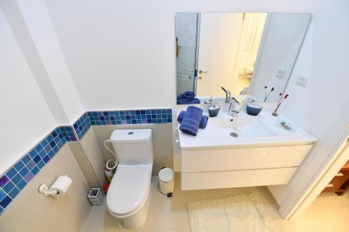 a bathroom with a toilet and a sink with a mirror at Turquoise Apartment with Pool in Eilat