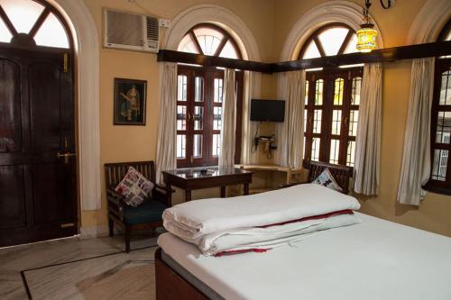 a bedroom with a bed and a desk and windows at Kanhaia Haveli in Pushkar