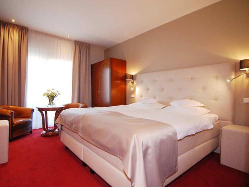 ein großes weißes Bett in einem Hotelzimmer in der Unterkunft Romantik Parkhotel het Gulpdal in Slenaken