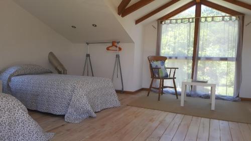 a bedroom with a bed and a chair and a window at Os Salguieiros (the Willows) in Pontevedra