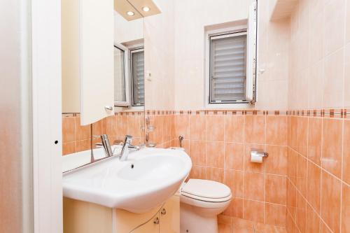 une salle de bain avec un lavabo, des toilettes et un miroir dans l'établissement Villa Matic, à Vela Luka