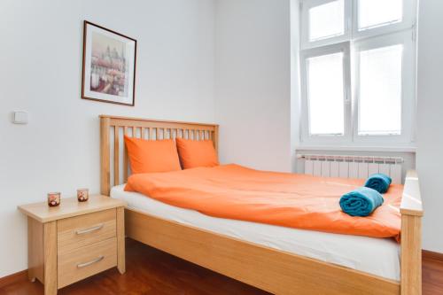 1 dormitorio con cama con sábanas de color naranja y ventana en Royal Apartment near river - Nek4th en Praga