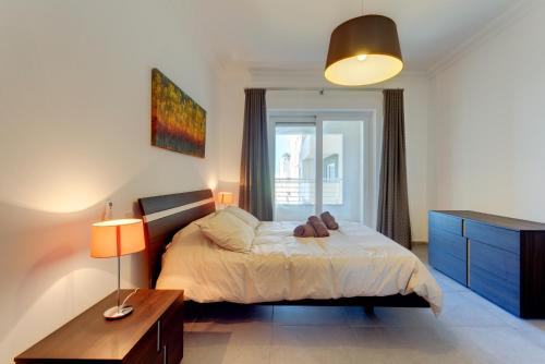 a bedroom with a bed and a dresser and a window at Seafront Apartment Sliema in Sliema