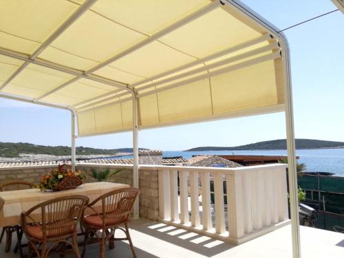 a white pergola on a balcony with a table and chairs at Apartments Dalmatino in Rukavac