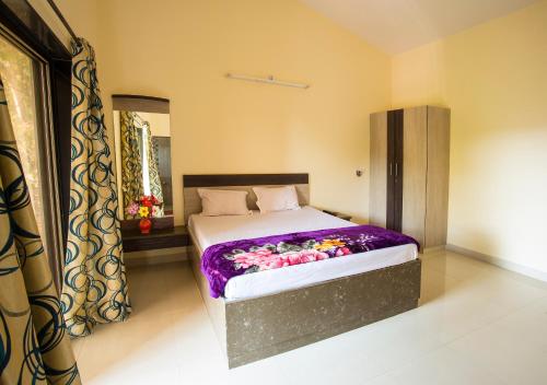 a bedroom with a bed with a purple blanket on it at Shri Laxmi Narayan Bungalow in Mahabaleshwar