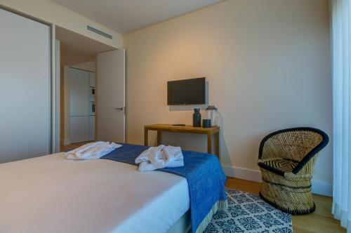 a bedroom with a bed and a chair and a television at Praia do Sal Resort in Alcochete