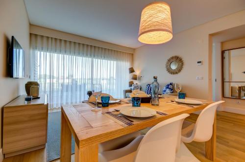 a dining room with a wooden table and white chairs at Praia do Sal Resort in Alcochete