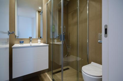 a bathroom with a toilet and a glass shower at Praia do Sal Resort in Alcochete