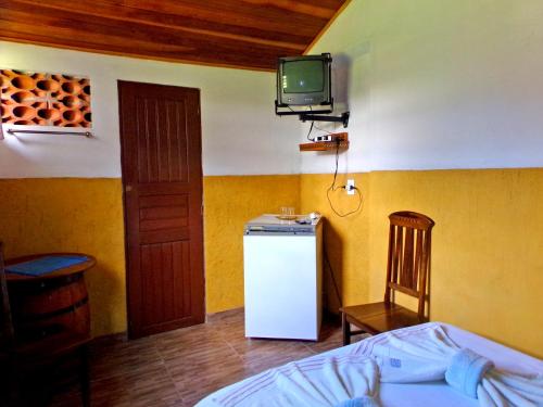 a room with a refrigerator and a tv on the wall at Quarto Maringá Minas in Bocaina de Minas