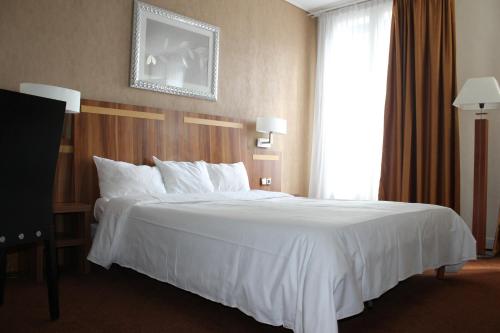 a bed in a hotel room with a white bedspread at Hotel The Originals du Grand Monarque Nantes Gare in Nantes