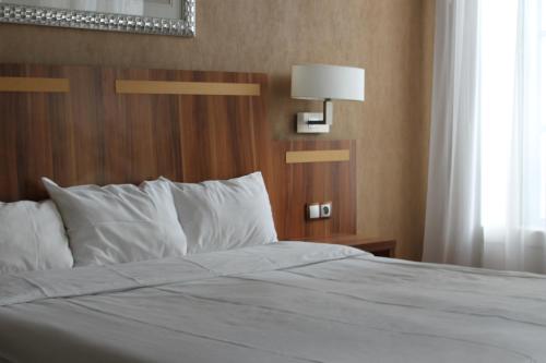 a bedroom with a white bed with a window at Hotel The Originals du Grand Monarque Nantes Gare in Nantes