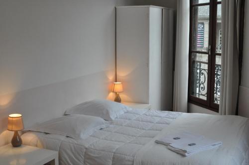 a bedroom with a white bed and a window at Cafe Hotel du Theatre in Dinan