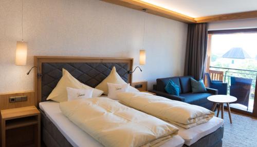 a hotel room with two beds and a chair at Garten - Hotel Sallerhof in Salzburg