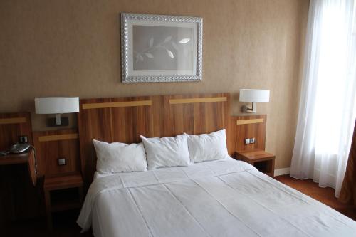 una camera da letto con un letto con lenzuola bianche e due lampade di Hotel The Originals du Grand Monarque Nantes Gare a Nantes