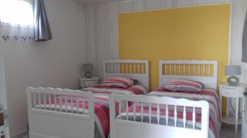 a bedroom with two white beds and a yellow wall at gîte vacances in Moncontour