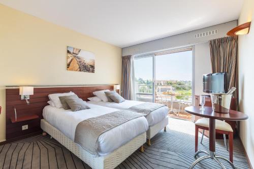 a hotel room with a large bed and a television at Hotel Brise de Mer - Piscine intérieure & extérieure in Saint-Raphaël