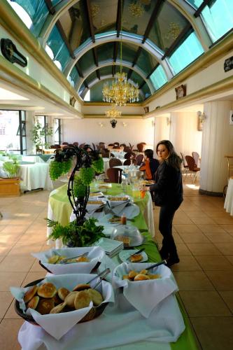 a woman standing in front of a table with plates of food at Hotel Eden By Bluebay in Oruro