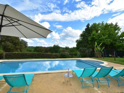 a swimming pool with chairs and an umbrella at Modern holiday home in Besse with private pool in Villefranche-du-Périgord