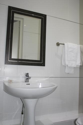 a white bathroom with a sink and a mirror at Hotel The Originals du Grand Monarque Nantes Gare in Nantes