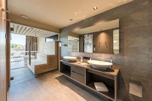 two sinks in a bathroom with a large mirror at Weinegg Wellviva Resort in Appiano sulla Strada del Vino