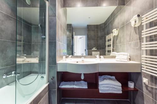 y baño con lavabo y ducha. en Hotel Brise de Mer - Piscine intérieure & extérieure en Saint-Raphaël