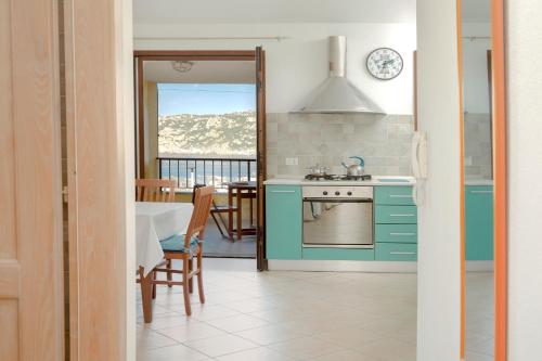 a kitchen with blue cabinets and a table with a view at Fronte Mare Capo Testa in Santa Teresa Gallura