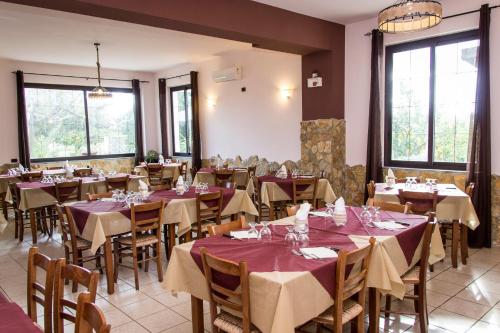 una sala da pranzo con tavoli, sedie e finestre di B&B Il Ristoro del Viandante a Caulonia